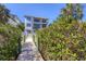 View from dock pathway featuring a multi-story home with multiple balconies and tropical landscaping at 7142 Hawks Harbor Cir, Bradenton, FL 34207