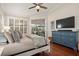 Bright bedroom featuring wood floors, a ceiling fan, dresser with TV, and slider doors to the lanai at 9422 Hawksmoor Ln, Sarasota, FL 34238