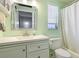Bright bathroom with a white vanity, square mirror and shower with a white curtain at 959 Cumberland Rd, Venice, FL 34293