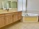 Bright bathroom featuring a soaking tub, wooden vanity with drawers and storage, and tiled floors at 11458 30Th E Cv, Parrish, FL 34219