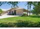 Home exterior featuring a well-manicured lawn, beautiful shrubbery, and three car garage at 11458 30Th E Cv, Parrish, FL 34219