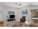 Spacious living room with a ceiling fan, large TV, and comfortable seating and seamless access to the patio at 11458 30Th E Cv, Parrish, FL 34219