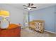 Cozy Bedroom features a wooden crib, ceiling fan, and soft neutral colors creating a peaceful and inviting space at 11571 Little River Way, Parrish, FL 34219