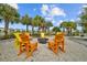 Outdoor firepit surrounded by orange Adirondack chairs offers a cozy gathering space for residents and guests at 11571 Little River Way, Parrish, FL 34219