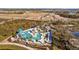 Aerial view of community pool with palm trees, slide, lounge chairs, and umbrellas at 11571 Little River Way, Parrish, FL 34219