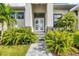 Close-up of the home's entrance featuring a modern white door, stone pathway, and decorative landscaping at 14322 Cando Ave, Port Charlotte, FL 33981