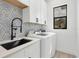 Clean laundry room with modern appliances, stylish backsplash, and ample storage in white cabinets at 14322 Cando Ave, Port Charlotte, FL 33981