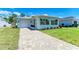 Inviting single-story home featuring a well-manicured lawn, paver driveway, and a charming light green exterior at 148 N Blvd Of The Presidents, Sarasota, FL 34236