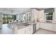 Modern kitchen open to living room featuring white cabinets, a spacious island, and stainless steel appliances at 16210 Isola Pl, Bradenton, FL 34211