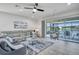 Stylish living area with reclining gray sofa, view of screened in patio, and ceiling fan at 17616 Bright Wheat Dr, Lithia, FL 33547