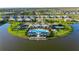 Aerial view of neighborhood pool, tennis courts, and clubhouse surrounded by tropical landscaping and a lake at 17827 Cherished Loop, Lakewood Ranch, FL 34211