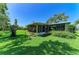 Exterior view of the home showcasing a screened-in porch, vibrant green lawn, and mature landscaping at 1809 67Th W St, Bradenton, FL 34209