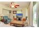 Cozy living room area with ceiling fan, TV setup, comfortable seating, and large glass sliding doors at 1809 67Th W St, Bradenton, FL 34209