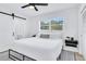 Modern bedroom featuring a large window, black ceiling fan, and barn door to bathroom at 1921 Fern Ave, Sarasota, FL 34235
