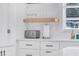 White kitchen counter featuring tile backsplash, floating wood shelf, and modern appliances at 1921 Fern Ave, Sarasota, FL 34235