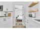 White kitchen with floating shelves leads into a bedroom; light and airy design at 1921 Fern Ave, Sarasota, FL 34235