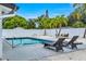 Backyard pool with lounge chairs and seating area surrounded by tropical landscaping and a white fence at 1921 Fern Ave, Sarasota, FL 34235
