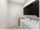 Well-lit laundry room with upper cabinets, sink, and modern white washer and dryer units at 19798 Cobblestone Cir, Venice, FL 34292