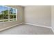 Well lit bedroom features carpeted floors and bright window with serene outdoor views at 2290 Beeville Ave, North Port, FL 34286