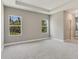 Spacious bedroom featuring tray ceiling, carpeted floors, and natural light from two large windows at 2290 Beeville Ave, North Port, FL 34286