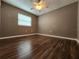 A secondary bedroom featuring a ceiling fan and neutral wall paint over sleek dark wood floors at 2300 Stickney Point Rd # 125, Sarasota, FL 34231