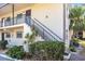 A side view of a condo building with stair access, complimented by lush shrubs and a verdant palm tree at 2300 Stickney Point Rd # 125, Sarasota, FL 34231