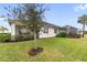 Lush backyard featuring a well-maintained lawn, mature trees, and a screened lanai at 256 Van Gogh Cv, Bradenton, FL 34212