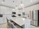 Modern kitchen with stainless steel appliances, white cabinets, island with bar stools, and stylish pendant lighting at 27061 Paradise Shores Dr, Englewood, FL 34223