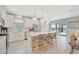 Bright, open kitchen boasts white cabinets, quartz countertops, island with seating, and sliding glass doors to the lanai at 27061 Paradise Shores Dr, Englewood, FL 34223