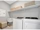 Functional laundry room with washer, dryer, sink, and overhead storage shelves at 27061 Paradise Shores Dr, Englewood, FL 34223