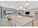 Open concept living area with large island, pendant lighting, tile floors, and view to lanai at 27061 Paradise Shores Dr, Englewood, FL 34223