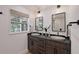 Bathroom featuring double sinks, dark wood cabinets, modern mirrors and large windows at 2833 Bay Shore Cir, Sarasota, FL 34234