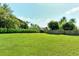 Expansive green backyard with a wooden fence, manicured hedges, and mature trees offers a private outdoor space at 3647 Country Place Blvd, Sarasota, FL 34233