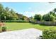 Lush backyard with a stone patio, wooden fence, and verdant landscaping create a serene outdoor space at 3647 Country Place Blvd, Sarasota, FL 34233