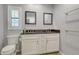 Modern bathroom featuring double sinks, a black granite countertop, and a window with plantation shutters at 3647 Country Place Blvd, Sarasota, FL 34233