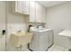 Functional laundry room with washer, dryer, utility sink, ample storage cabinets, and tiled flooring at 3647 Country Place Blvd, Sarasota, FL 34233