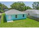 Low aerial view of light teal single Gathering home displaying the backyard, door, and light gray roof at 3712 19Th E St, Bradenton, FL 34208