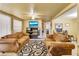 Inviting living room with tan couches, TV, ceiling fan, and black and white swirl patterned rug at 409 Olive Ave, Nokomis, FL 34275