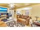 Comfortable living room featuring a brown couch, TV, ceiling fan, and black and white swirl patterned rug at 409 Olive Ave, Nokomis, FL 34275