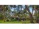 Backyard with mature trees, screened-in porch and outdoor seating area at 4916 Hidden Oaks Trl, Sarasota, FL 34232
