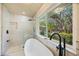 Bright bathroom with free-standing tub, glass shower, and backyard view at 4916 Hidden Oaks Trl, Sarasota, FL 34232
