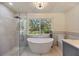 Bright bathroom with free-standing tub, glass shower, and backyard view at 4916 Hidden Oaks Trl, Sarasota, FL 34232