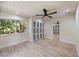 Bright bedroom with light wood floors, ceiling fan, and view of the surrounding landscaping at 4916 Hidden Oaks Trl, Sarasota, FL 34232