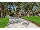 Paver driveway leading to a single-story home surrounded by lush greenery and trees at 4916 Hidden Oaks Trl, Sarasota, FL 34232