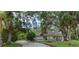 A home nestled among lush trees showcasing the front yard and the beautiful landscaping at 4916 Hidden Oaks Trl, Sarasota, FL 34232
