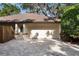Attached two-car garage with a brick-paved driveway, white door and exterior, and partial landscaping at 4916 Hidden Oaks Trl, Sarasota, FL 34232
