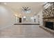 Open-concept living room featuring a stone fireplace, modern ceiling fan, and updated kitchen in the background at 4916 Hidden Oaks Trl, Sarasota, FL 34232
