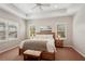 Well-lit bedroom with a king-sized bed, tray ceiling, ceiling fan, and two windows with shutters at 5023 Brickell Park Cv, Bradenton, FL 34211