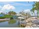 View of boat lift with boat on the canal, surrounded by palm trees and waterfront properties under a clear sky at 526 56Th St, Holmes Beach, FL 34217