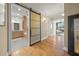 Hallway with hardwood floors leads to a bathroom with custom cabinets and a sliding frosted glass door at 526 56Th St, Holmes Beach, FL 34217